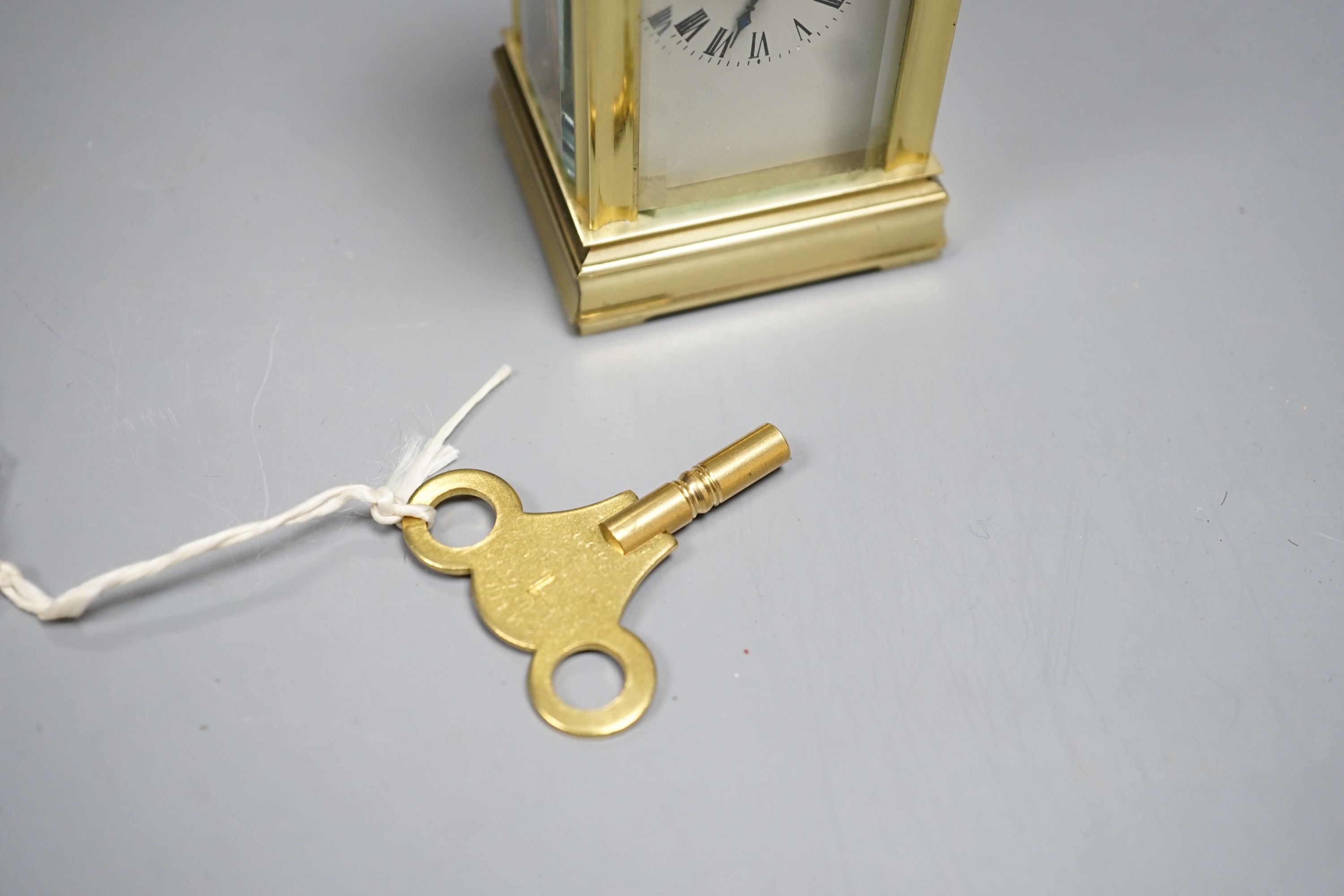 A small brass carriage time piece and key 9cm